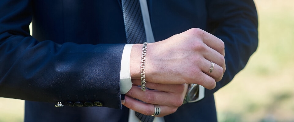 Mężczyzna w garniturze z biżuterią na dłoniach.